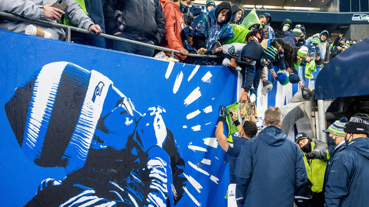 Seattle Seahawks quarterback Russell Wilson (3) signs as many autographs as he can as he walks off the field after leading his team to a 51-29 win over the Detroit Lions on Sunday, Jan. 2, 2022, at Lumen Field in Seattle.