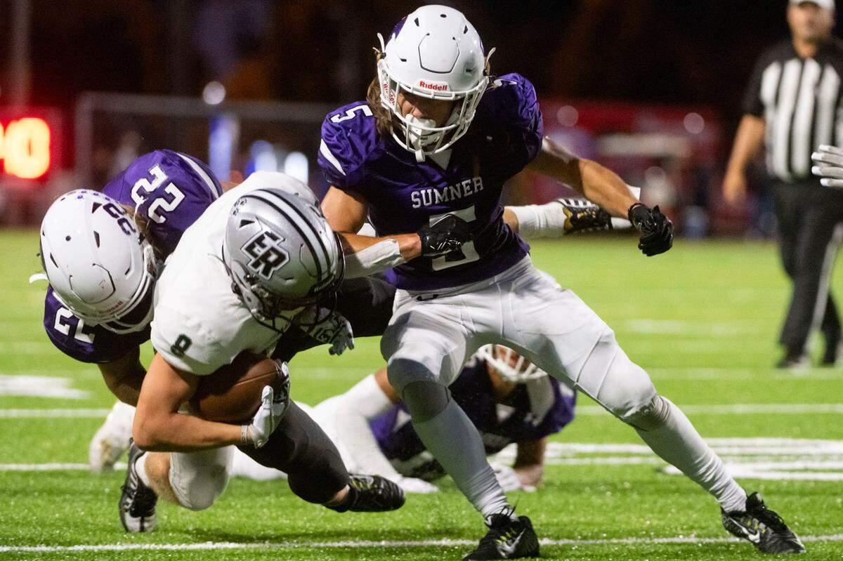 Sumner’s Kade Jindra (5) and Matthew Spurbeck tackle Emerald Ridge receiver Gio Kafentzis during the second quarter of a 4A SPSL game on Friday, Sept. 16, 2022, at Sunset Chev Stadium in Sumner, Wash.