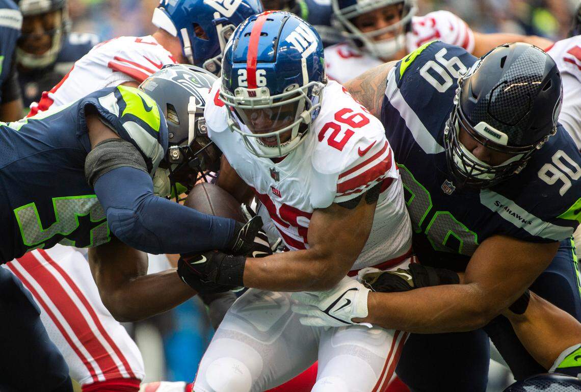 Seattle Seahawks linebacker Boye Mafe (53) and Seattle Seahawks defensive tackle Bryan Mone (90) tackle New York Giants running back Saquon Barkley (26) in the first quarter of an NFL game at Lumen Field in Seattle, Wash. on Oct. 30, 2022. The Seahawks defeated the Giants 27-13.