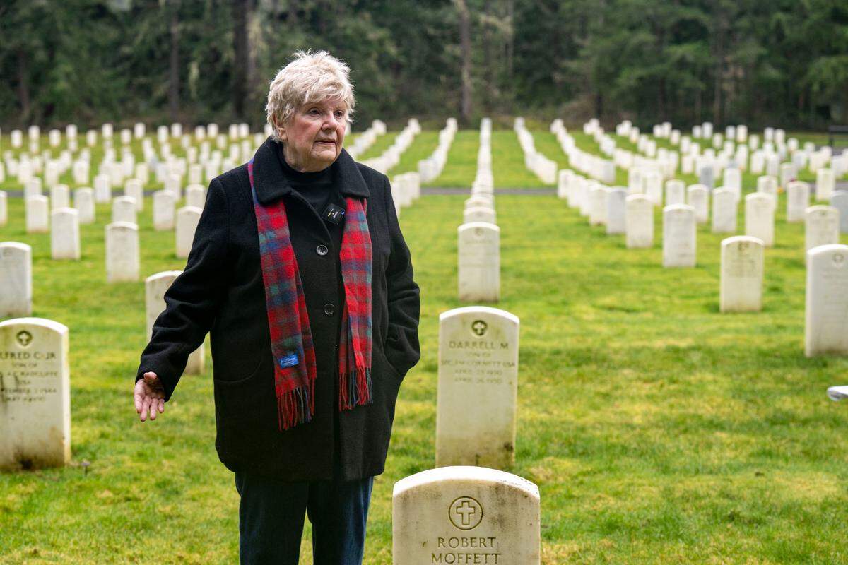 Mary Dowling stands alongside the grave of her husband, Robert Dowling, while pointing toward the site where she was supposed to be buried alongside him on Tuesday, Jan. 24, 2023, in the Camp Lewis Cemetery at Joint Base Lewis McChord.