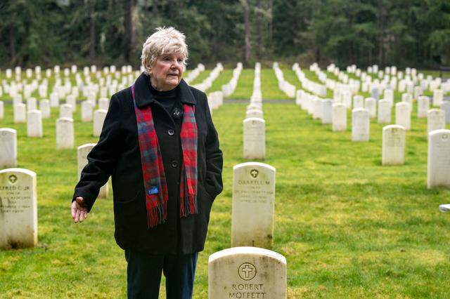 Mary Dowling stands alongside the grave of her husband, Robert Dowling, while pointing toward the site where she was supposed to be buried alongside him on Tuesday, Jan. 24, 2023, in the Camp Lewis Cemetery at Joint Base Lewis McChord.