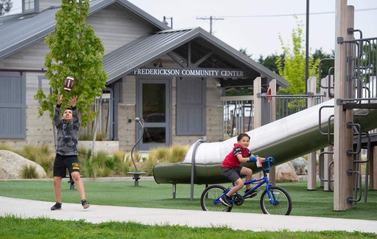 Kalani Park, 13, and his brother, Michael Park, 8, play outside the Frederickson Community Center at Cross Park in Frederickson, Washington on Tuesday, May 24, 2022. The former dairy barn was renovated as an event center, retaining many of the historic features.