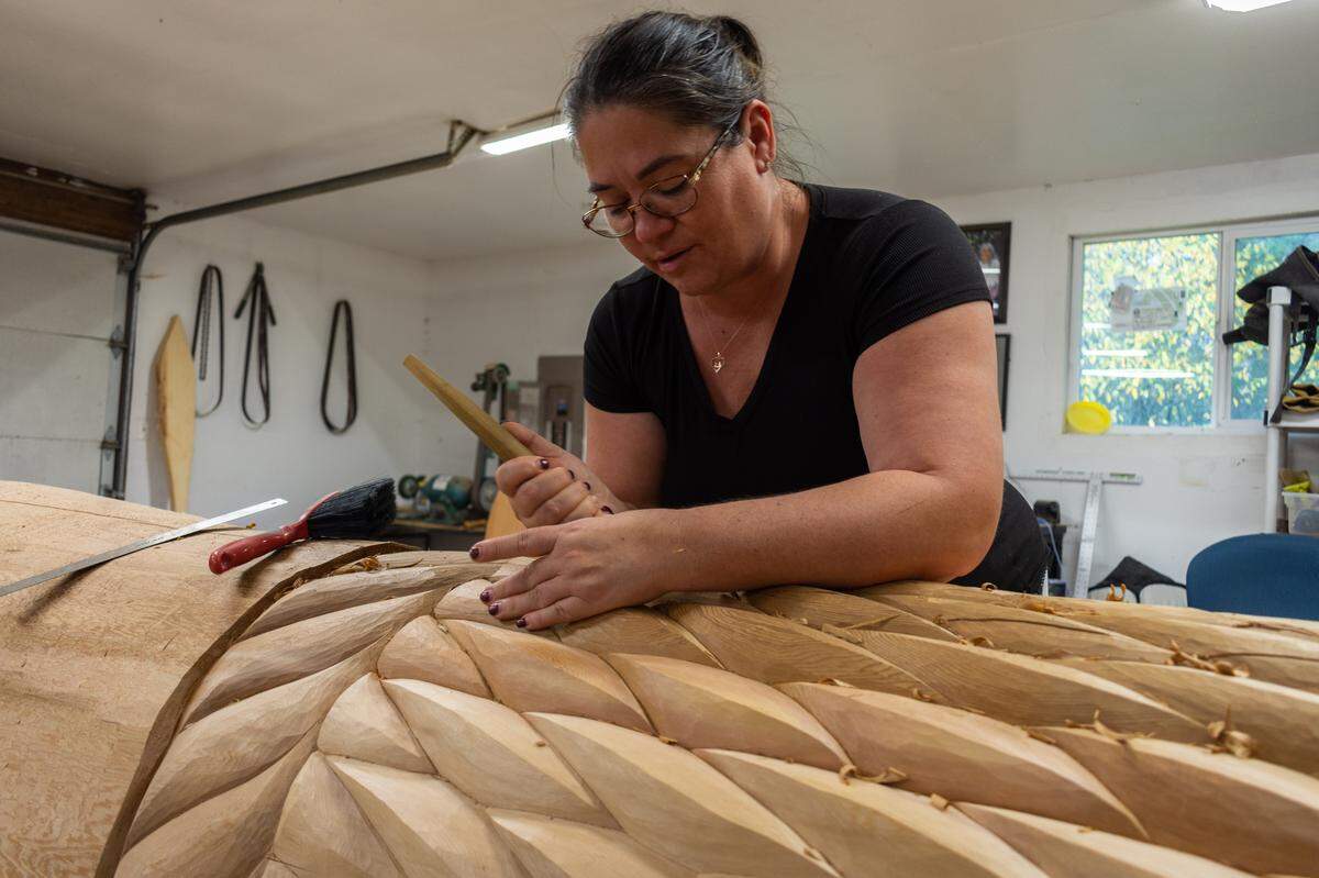 Andrea Wilbur-Sigo, a member of the Squaxin Island Tribe, carves a rope-like basket into a yellow cedar log at her home workshop in Shelton, Wash, on Thursday, Nov. 4. The carver is known for large pieces of public art including welcome figures, house posts and spindle whorls as well as beading and weaving.
