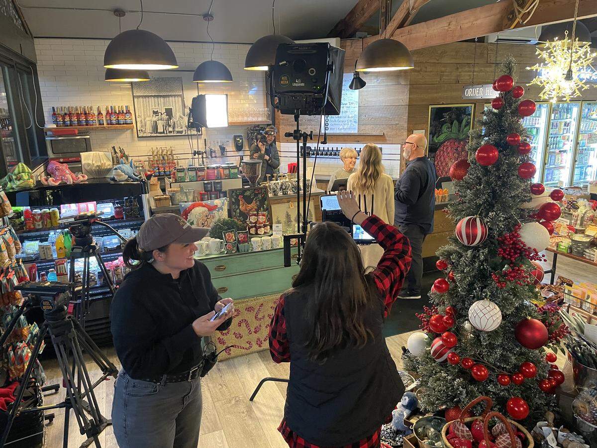 Production crew members for the reality TV show “House Hunters” watch as the couple featured in the episode talk to barista Sunny Willson at Olalla Bay Market & Landing in Olalla, Wash.