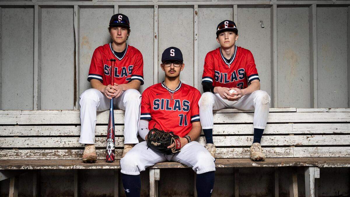 Silas High School varsity baseball players Gavin Yoder, left, Joseph Gutierrez, center, and Nathan Eisenmenger, right, pose for a portrait in the dugout at Silas High School on Thursday, April 21, 2022 in Tacoma, Wash.