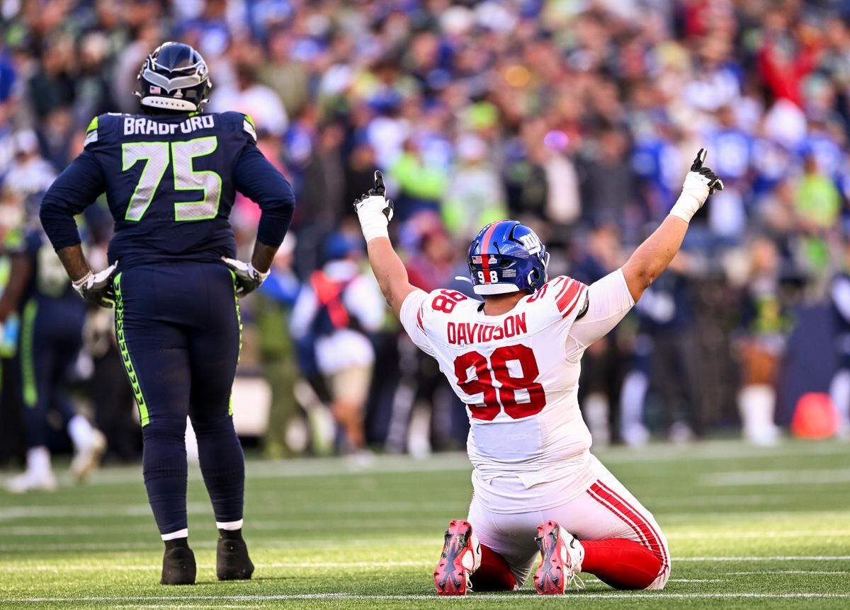 New York Giants defensive tackle D.J. Davidson (98) and Seattle Seahawks guard Anthony Bradford (75) react to a block field goal attempt that was ran back for a touchdown in the closing seconds of the game at Lumen Field, on Sunday, Oct. 6, 2024 in Seattle, Wash.