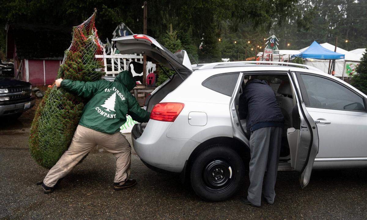 Jordan Boyd loads a Christmas tree for a customer at Patterson’s Farm Market in Gig Harbor, Washington, on Tuesday, Dec. 20, 2022.