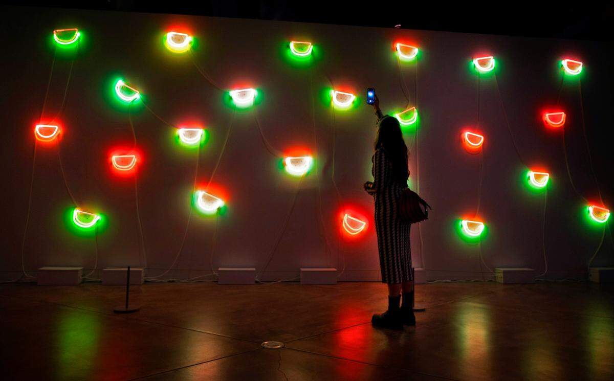 Lily Reeves, an artist from Phoenix, Arizona, snaps a photo of Jude Abu Zaineh’s “Tend to Grow” art piece during the “She Bends: Redefining Neon Legacy” art exhibit at the Museum of Glass in downtown Tacoma, Washington, on Saturday, Feb. 11, 2023. Reeves was at the exhibit to display her neon artwork “Room to Breath.”
