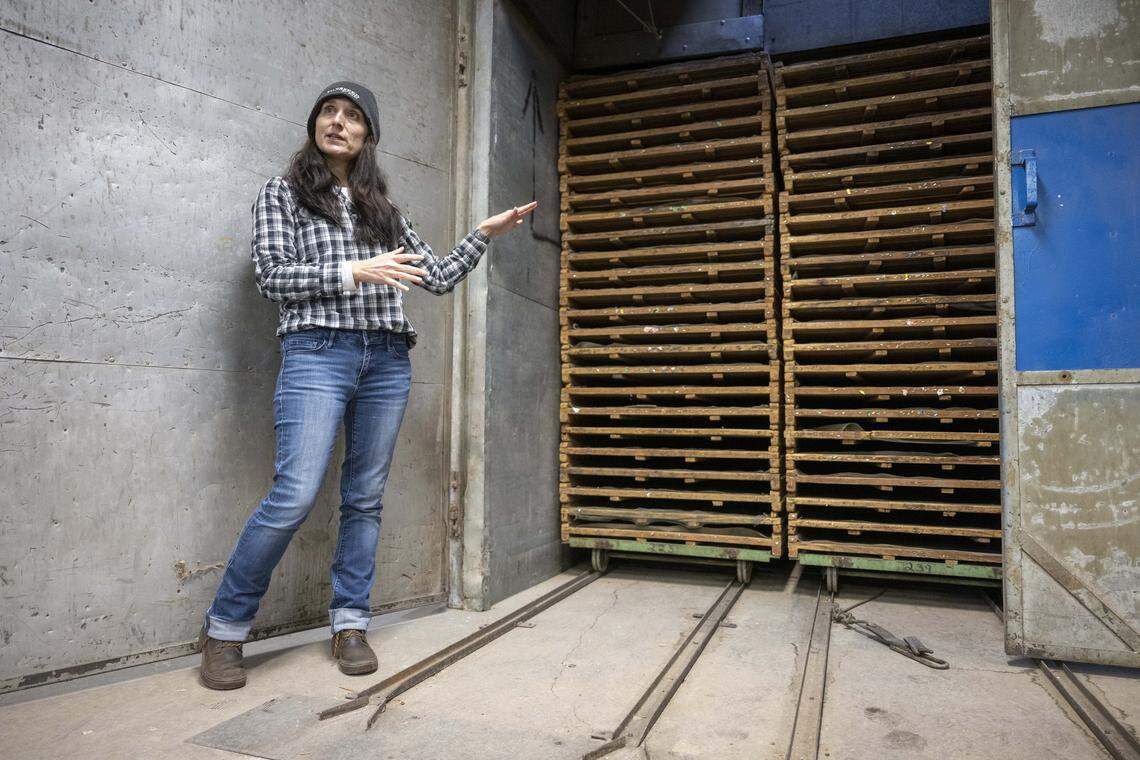 Kea Woodruff, the Silvaseed general manager, stands next to a kiln used to heat-dry cones in Silvaseed's conifer seed extracting process on Tuesday, Dec. 2, 2025, in Roy, Wash.