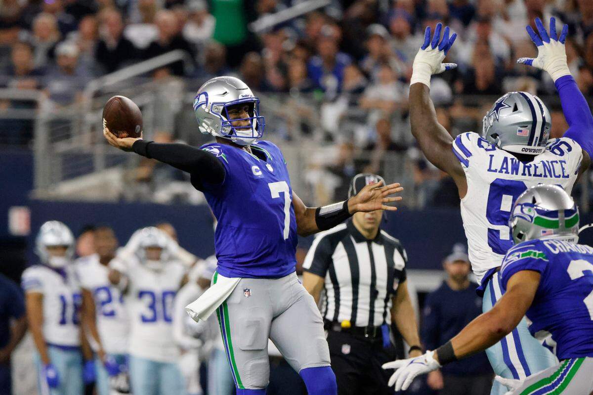 Seattle Seahawks quarterback Geno Smith (7) throws a touchdown pass to DK Metcalf, not pictured, under pressure from Dallas Cowboys defensive end DeMarcus Lawrence (90) in the second half of an NFL football game in Arlington, Texas, Thursday, Nov. 30, 2023. (AP Photo/Michael Ainsworth)