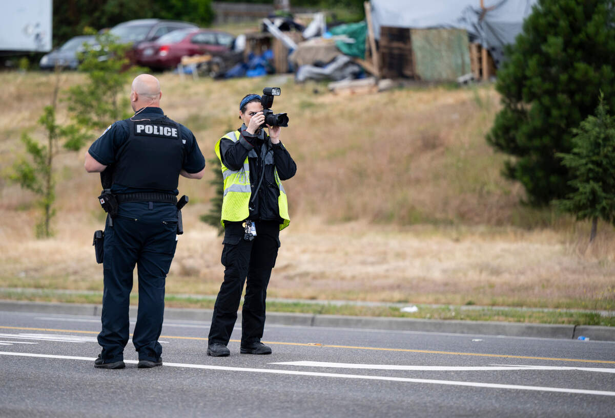 An officer and crime scene technician investigate a drive by shooting at the intersection of South Tacoma Way and South 47th Street in Tacoma, Wash. on Sunday, July 3, 2022. An adult male was shot in a vehicle and transported to the hospital with serious injuries, according to the Tacoma Police Department.