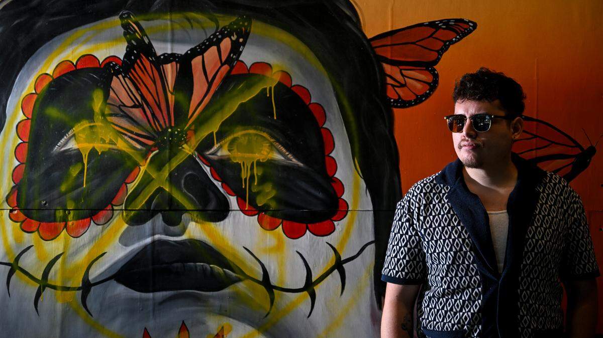 Gerardo Peña poses with his mural titled “The Monarch Butterfly” at ALMA Cafe, Friday, Aug. 18, 2023, in Tacoma, Wash.