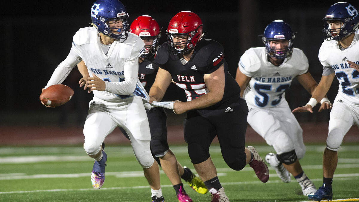 Gig Harbor quarterback Cade Dessert is reeled in by Yelm defensive lineman Aiden Paddock for a sack during Friday night’s 3A SSC football game at Yelm High School on Sept. 27, 2019.