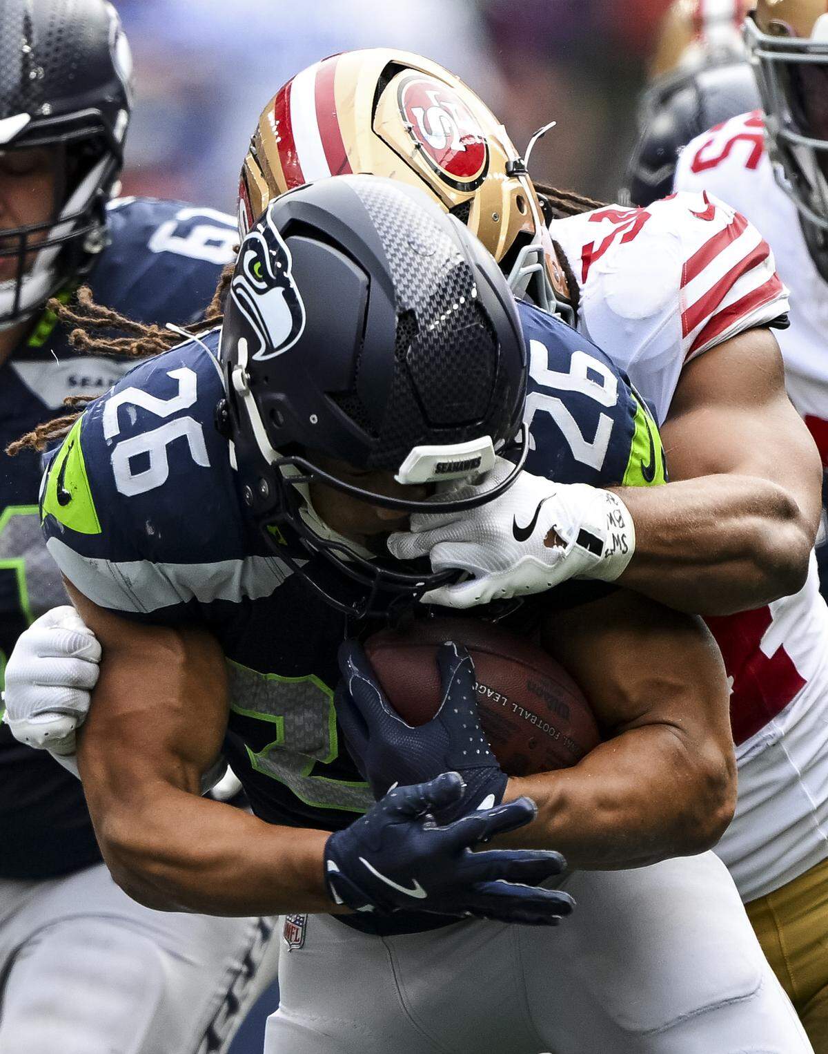 Seattle Seahawks running back Zach Charbonnet (26) picks up 7-yards on the run as San Francisco 49ers linebacker Fred Warner (54) gets his hand in his mask during the fourth quarter of the game at Lumen Field, on Sunday, Sept. 7, 2025, in Seattle.