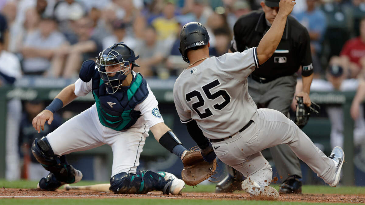 New York Yankees’ Gleyber Torres (25) scores on a hit by Andrew Benintendi ahead of the throw with Seattle Mariners catcher Cal Raleigh, left, who waits for the ball during the third inning of a baseball game, Monday, Aug. 8, 2022, in Seattle. (AP Photo/John Froschauer)