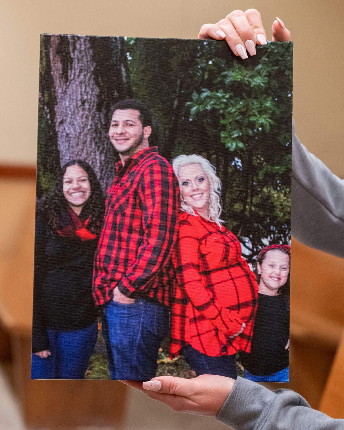 Christina Feeder, 37, the fiancee of murder victim Lawrence Andre Jeffries holds up a picture of her with him and their family that she brought to Pierce County Superior Court with her for a sentencing hearing on Friday, April 22, 2022, in Tacoma, Wash. Jeffries killer, Andrew Pointer, was sentenced to 40 years in prison.