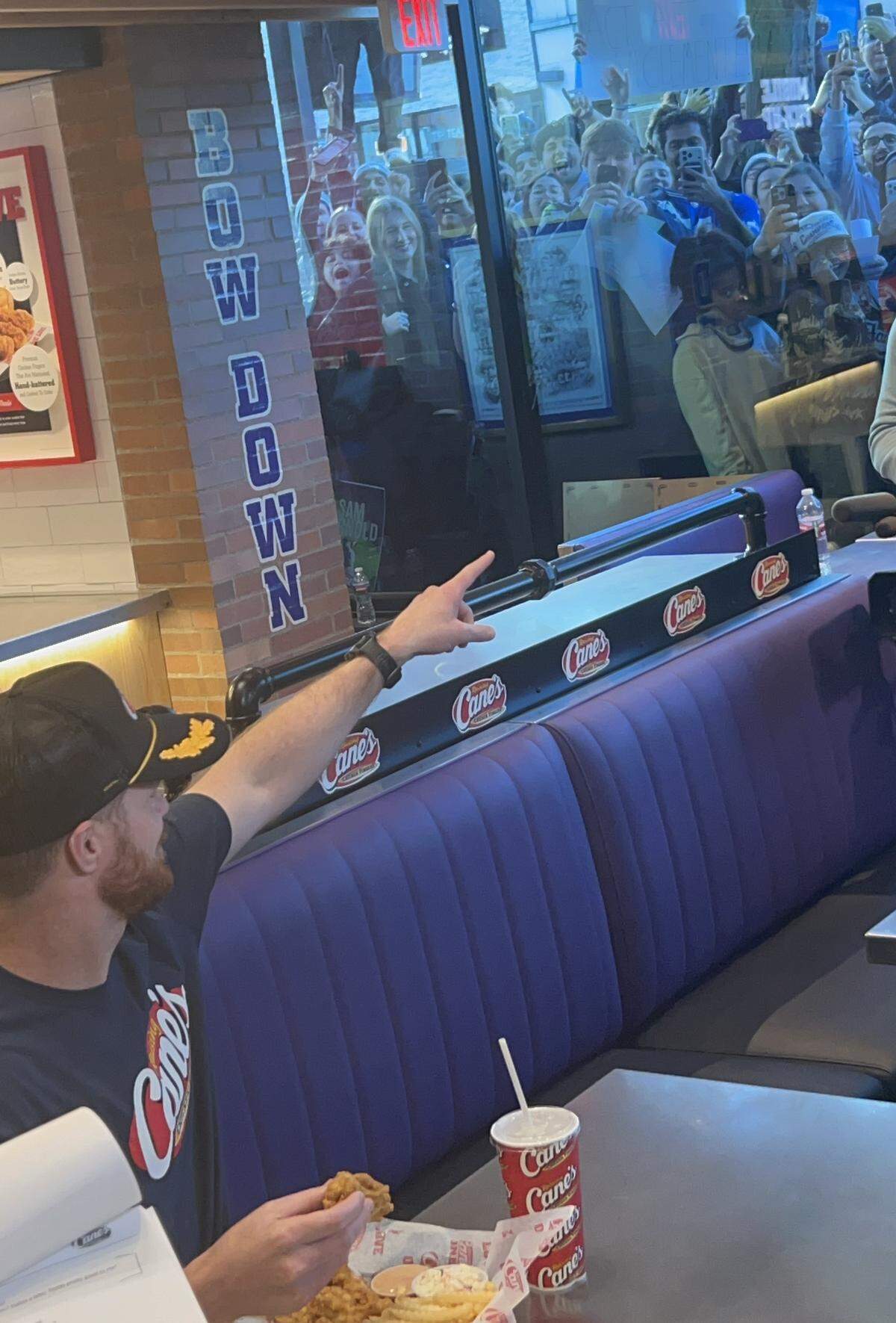 Super Bowl-winning Seahawks quarterback Sam Darnold points to acknowledge fans cheering him through a window of the new Raising Cane's in Seattle’s University District Darnold had a “soft opening” for Tuesday, Feb. 10, 2026.