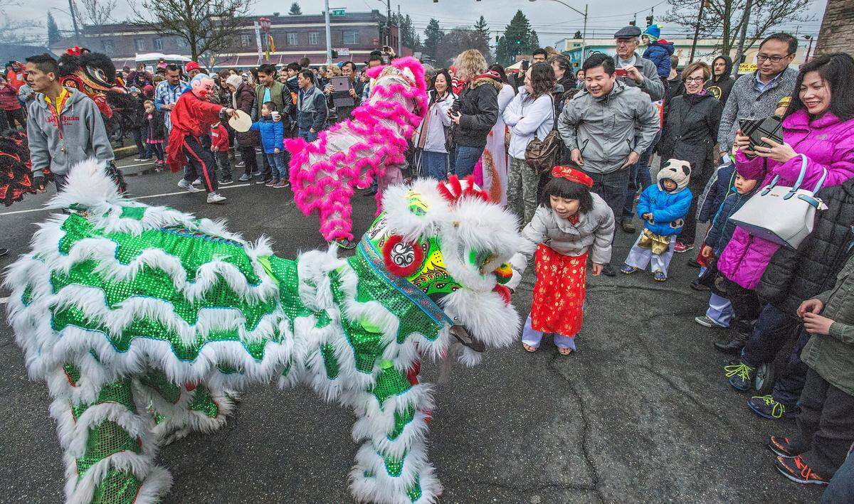 Vicky Nguyen, 9 of Puyallup, feeds a money offering to a lion dancer during a Lunar New Year celebration in the Lincoln Business District of Tacoma in 2016.