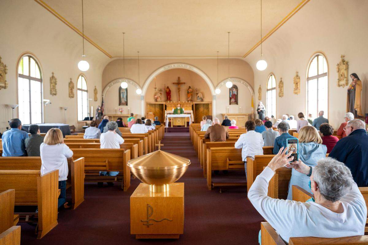 A woman takes a photo documenting the final mass at St. Rita of Cascia on Wednesday, June 8, 2022, in Tacoma.