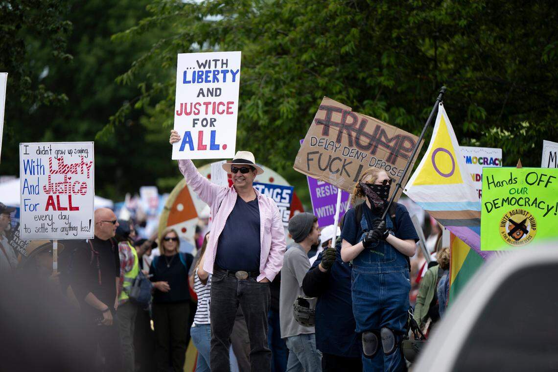 People gather and wave anti-Trump signs during a No Kings” protest at People’s Park on Saturday, June 14, 2025, in Tacoma, Wash.