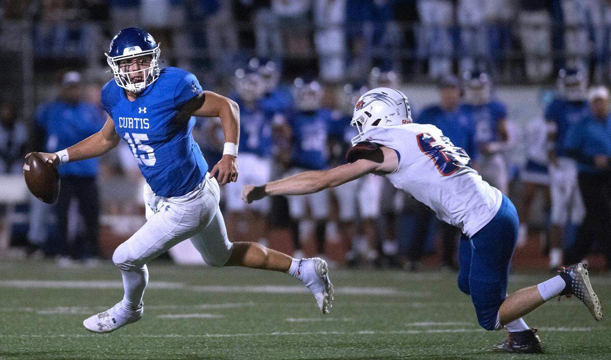 Curtis quarterback Rocco Koch scrambles away from Graham Kapowsin defensive lineman Jonathan Haas during Friday night’s 4A SPSL football game at Viking Stadium in University Place, Washington, on Oct. 6, 2023. Graham Kapowsin won the game, 42-35.