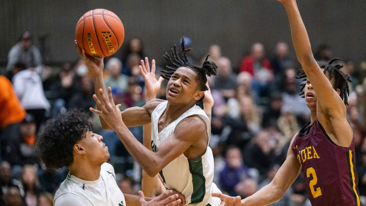 Auburn guard Jaylen Petty (3) drives to the basket for an off-balance shot as O’Dea guard Mason Williams (2) defends during the first quarter of a Class 3A state regionals game on Saturday, Feb. 25, 2023, at Auburn High School in Auburn, Wash.