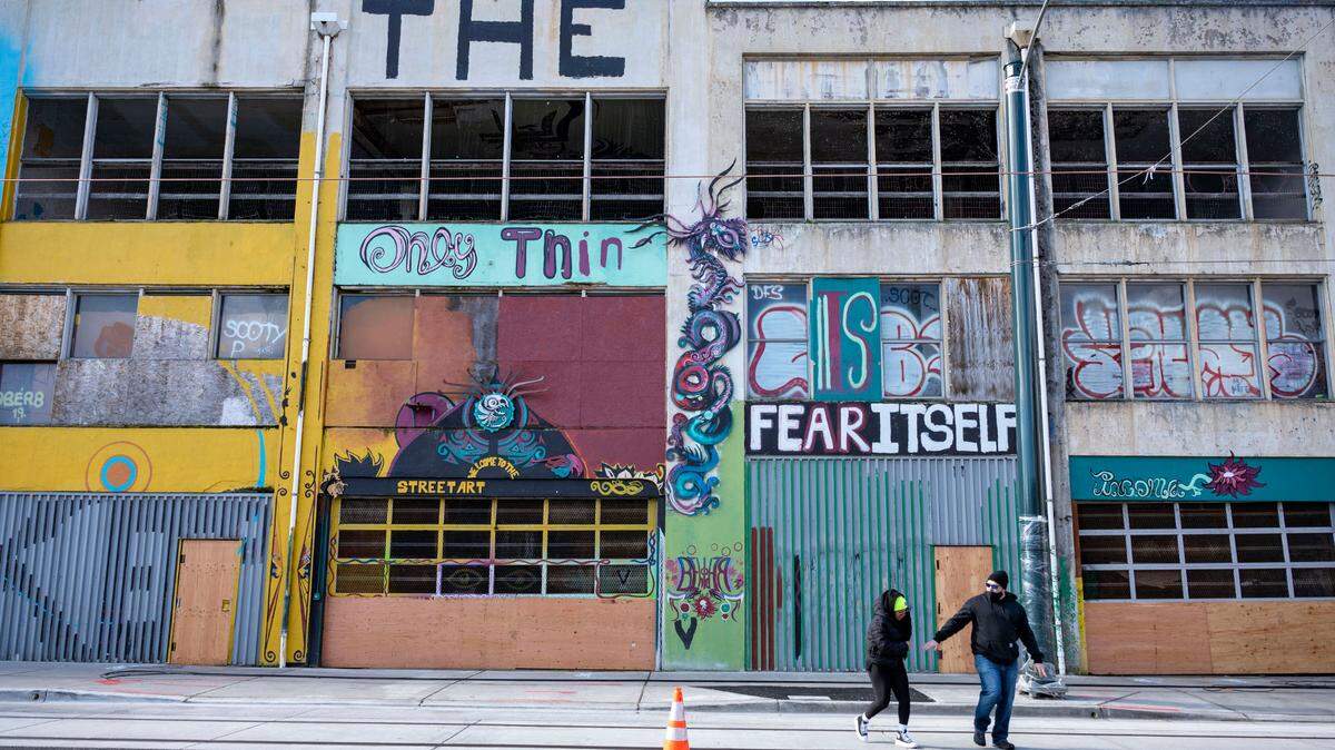 People walk across the street in front of the Graffiti Garages in the 700 block of Commerce Street in downtown Tacoma on Tuesday, Feb. 22, 2022. Plans have been submitted for the building to be demolished and replaced with an apartment building.