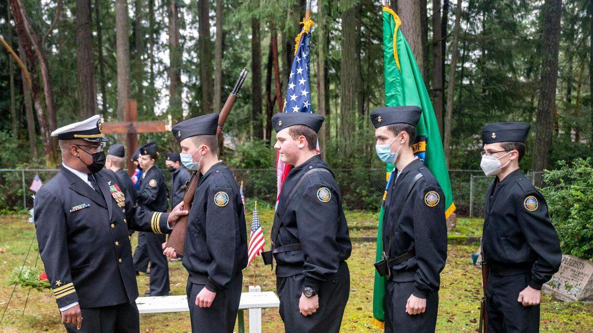 The Peninsula Navy National Defense Cadet Corps color guard Grayson McKee (left-center), Alex Hardy (center), Mason Elliott (right-center) and Tate Kamasz are instructed by Lieutenant Commander Darrell Hood as they practice before presenting the colors to open a Wreaths Across America ceremony at Artondale Cemetery in Gig Harbor, Wash., on Saturday, Dec. 18, 2021.