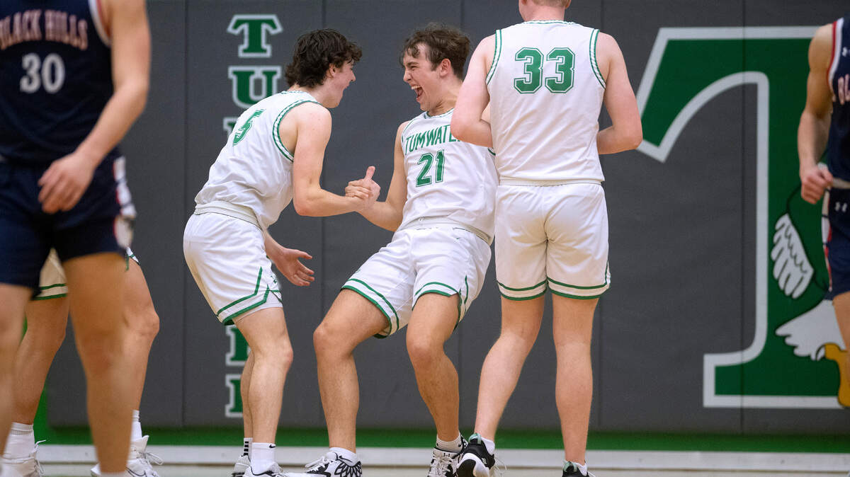 Tumwater’s Connor Hopkins (21) celebrates with teammates Luke Reid and Tanner Brewer after drawing an offensive foul against the Black Hills Wolves during Tuesday night’s crosstown rivalry boys basketball game at Tumwater High School in Tumwater, Washington, on Jan. 31, 2023. Tumwater won the game, 58-38.