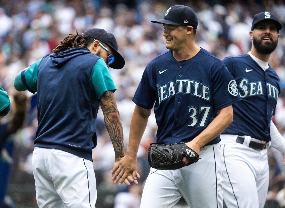Seattle Mariners relief pitcher Paul Sewald (37) high-fives Seattle Mariners shortstop J.P. Crawford (3) as he walks off the field after defeating the New York Yankees 4-3 to win their first season series finale against the Yankees in 20 years, after the game at T-Mobile Park in Seattle, Wash. on August 10, 2022.