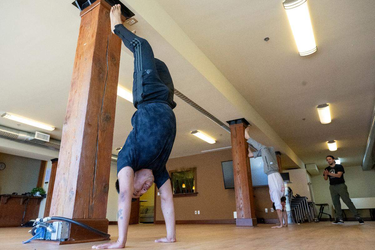 Israel Alvarez, left, and Anthony Asher, center, stand on their hands under the watch of instructor True “De Verdade” Emeka during a Capoeira class, or the Afro-Brazilian art form of martial art and dance, on Friday, April 18, 2025, at the Tacoma Capoeira Center in Tacoma.