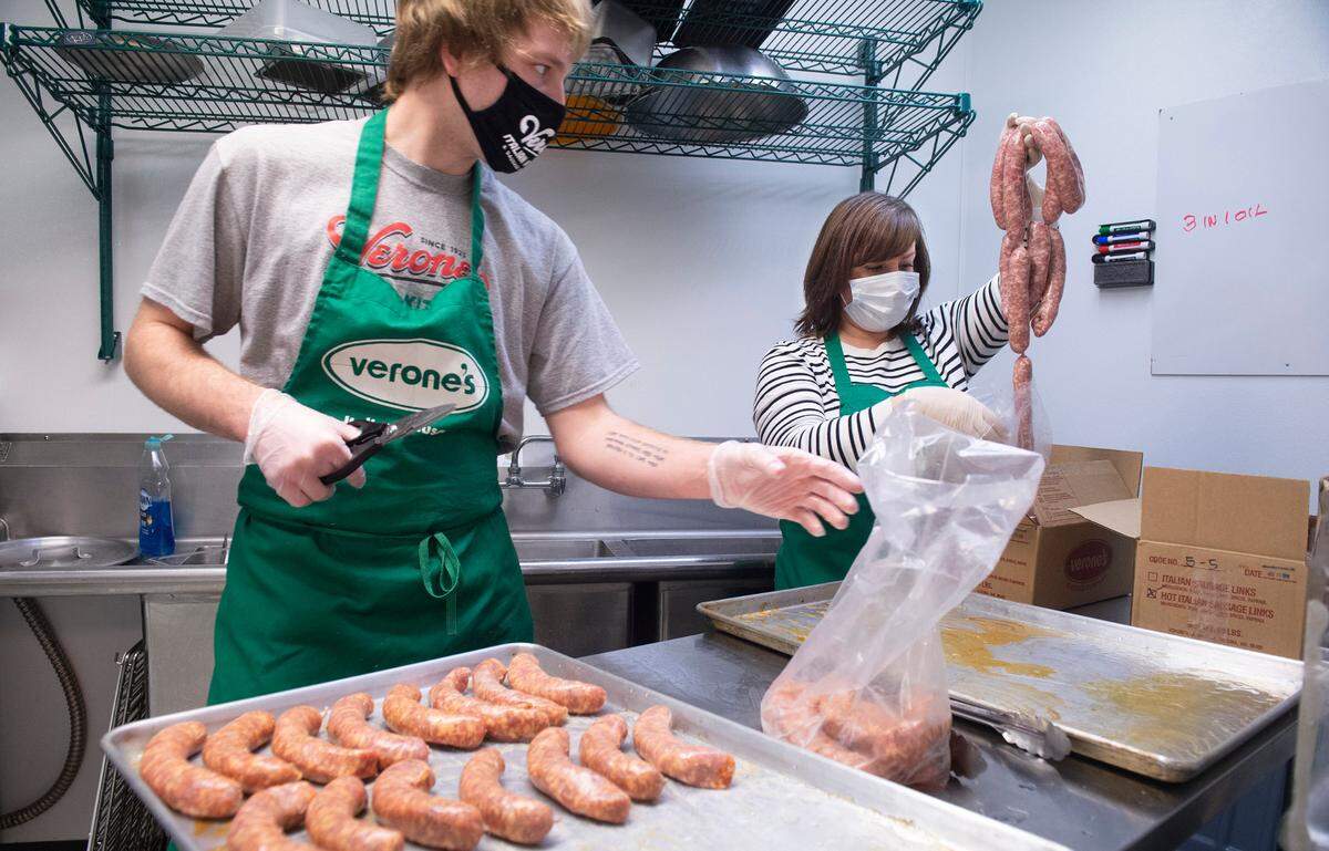 Austin McDonald and Renee Verone prepare Italian sausage for the oven at the Verone’s Italian Kitchen & Sausage Company in Fircrest, Washington, on Tuesday, Dec. 22, 2020. The family closed the market and its wholesale business on April 30.