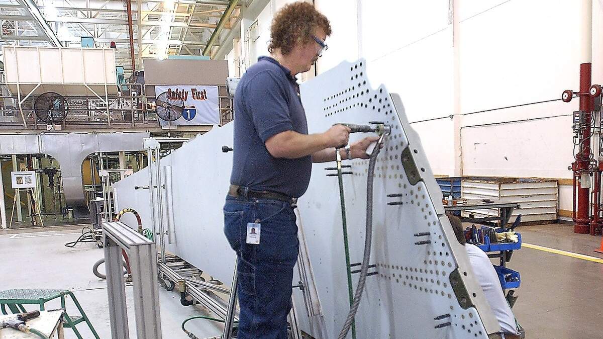 At the Boeing Frederickson Plant in Pierce County in 2004, assembly mechanics attach titanium fittings to a 777 vertical fin skin panel.