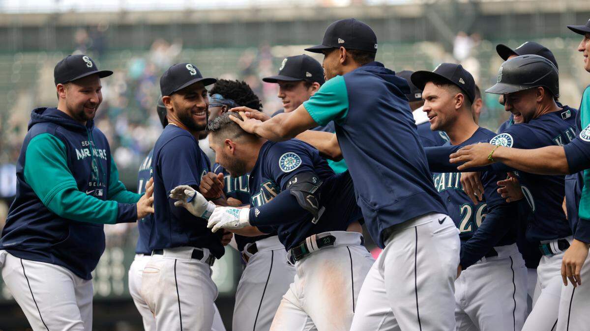 Seattle Mariners players surround and rub the head of Ty France after he drove in the winning run of the 5-4 over the Detroit Tigers during the ninth inning a baseball game, Wednesday, Oct. 5, 2022, in Seattle. (AP Photo/John Froschauer)