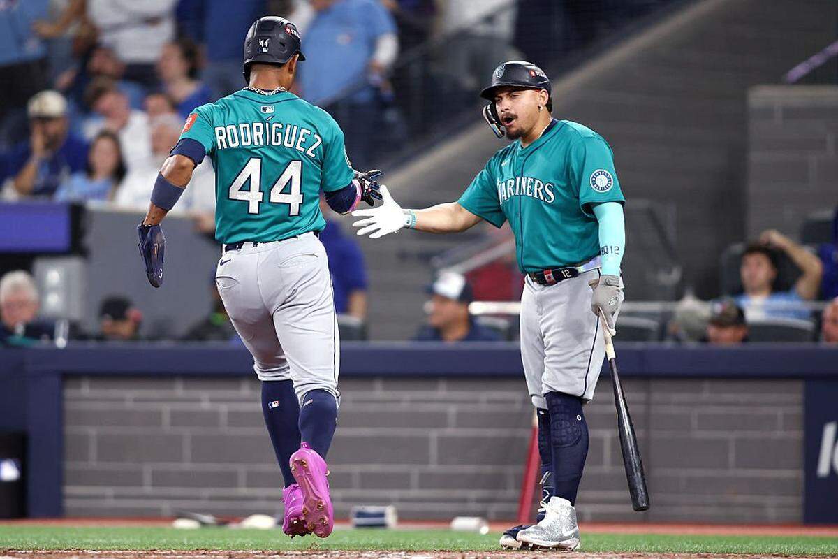 TORONTO, ONTARIO - OCTOBER 12: Julio Rodriguez #44 of the Seattle Mariners is congratulated by Josh Naylor #12 after scoring a run on a single by Jorge Polanco #7 during the sixth inning against the Toronto Blue Jays in game one of the American League Championship Series at Rogers Centre on October 12, 2025 in Toronto, Ontario. (Photo by Cole Burston/Getty Images)