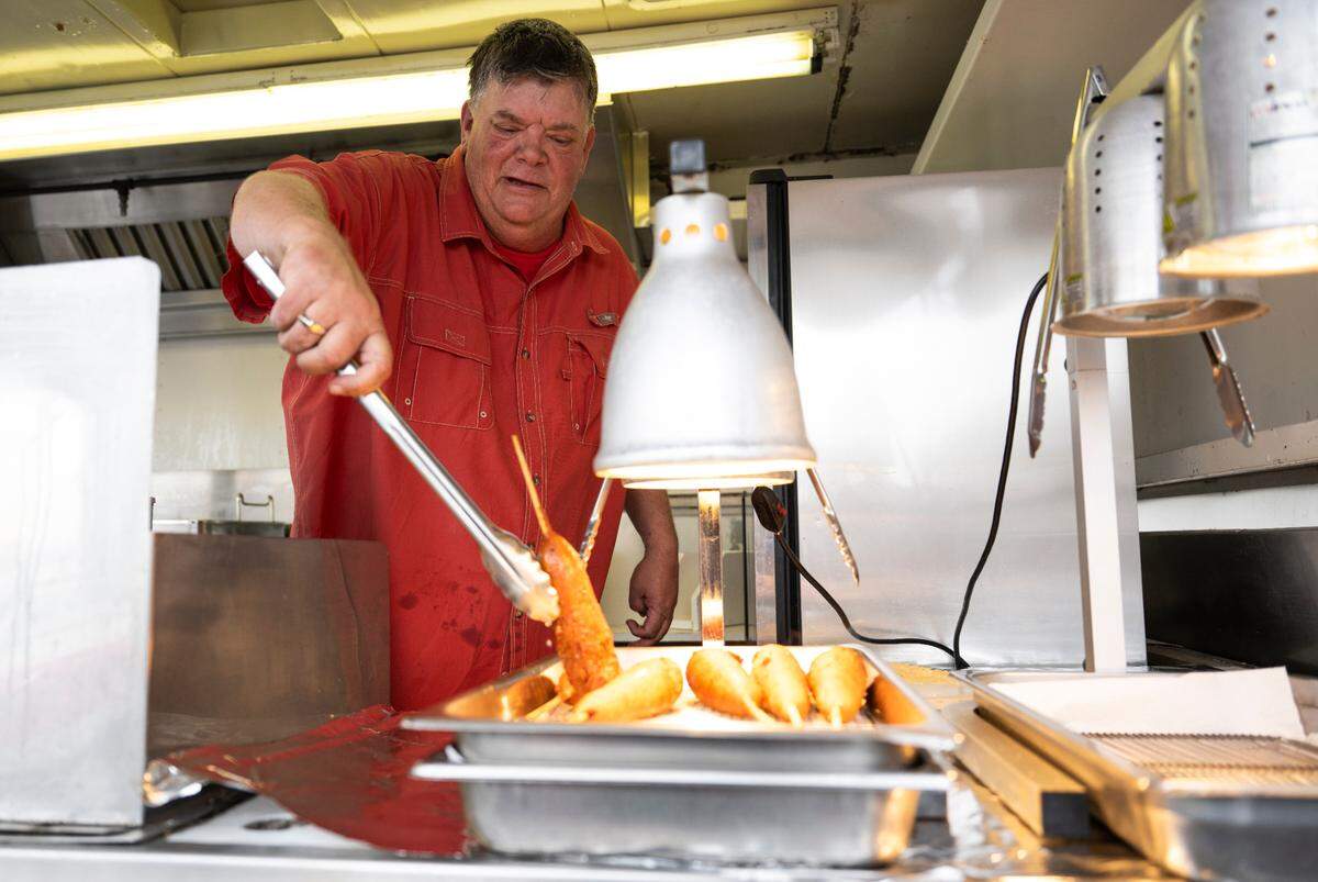Owner Mike Christensen of Sales Family pulls fresh, hot Krusty Pups from the fryer at the Washington State Fair, Thursday, Aug. 31, 2023, Puyallup, Wash.