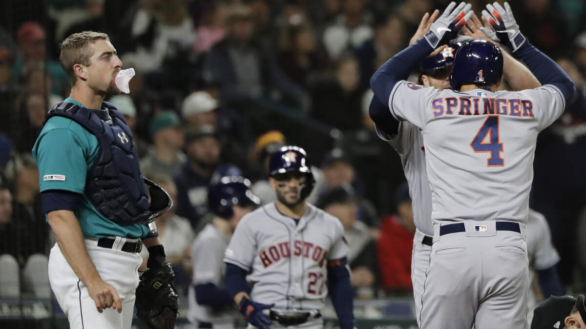 Seattle Mariners catcher Tom Murphy, left, pops a gum bubble as Houston Astros’ George Springer (4) is greeted by Jake Marisnick after Springer hit a two-run home run to score Marisnick during the third inning of a baseball game, Friday, April 12, 2019, in Seattle. (AP Photo/Ted S. Warren)