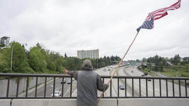 Who is that man waving an upside-down American flag near the Tacoma Dome on I-5?