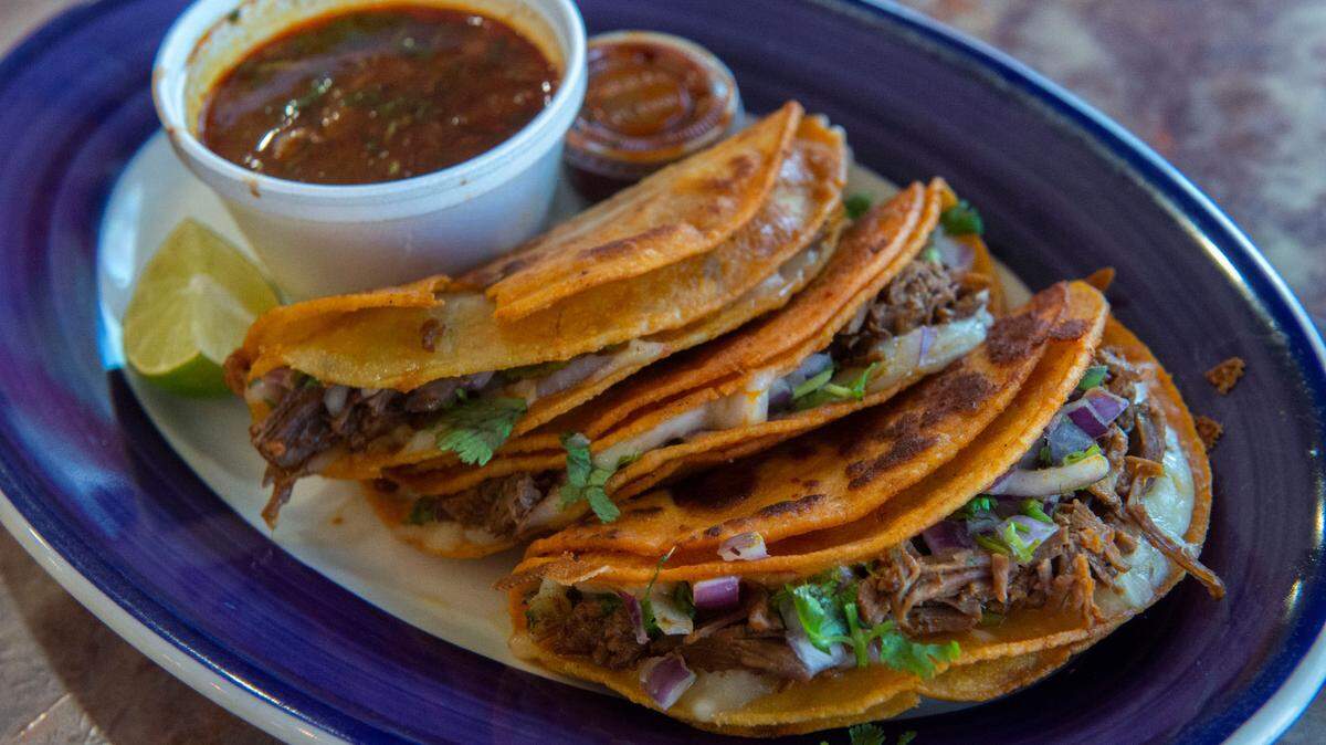 Quesabirrias, a popular trend at Mexican restaurants like Los Tamales, are made with marinated beef (barbacoa) and cheese folded into a fried tortilla with a side order of consome for dipping.