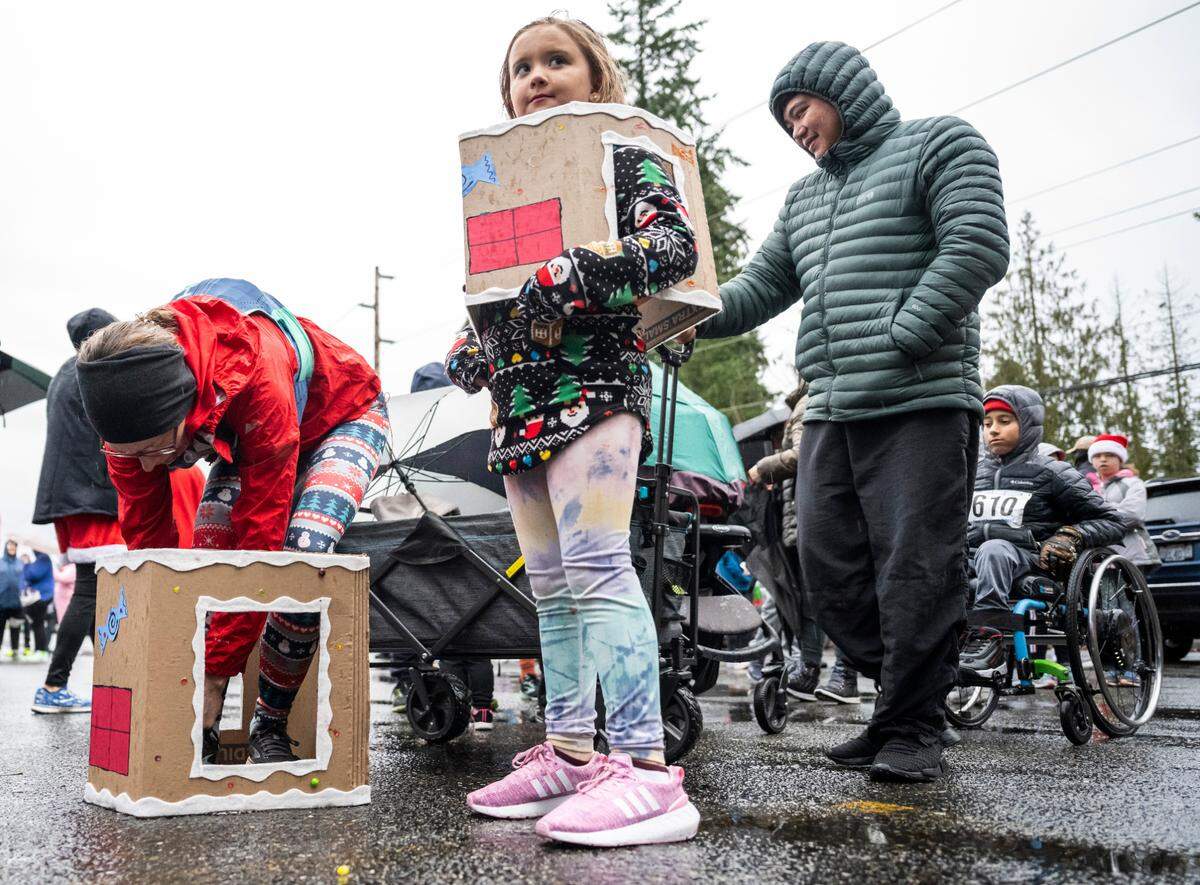 Ashley Delduca, left, ties her shoe as she prepares to run in the 5th Annual Christmas Eve Ugly Sweater 5K with her daughter, Carly Delduca, center, on the Nathan Chapman Memorial Trail in Puyallup, Wash. on Dec. 24, 2022.