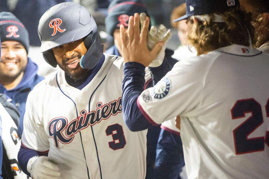 Tacoma catcher Josh Morgan (3) gets a high five as he walks through the dugout after hitting a solo home run to give the Rainiers a 4-2 lead in the bottom of the seventh inning during the season opener against the Salt Lake Bees at Cheney Stadium in Tacoma, Wash., Tuesday, April 5, 2022.