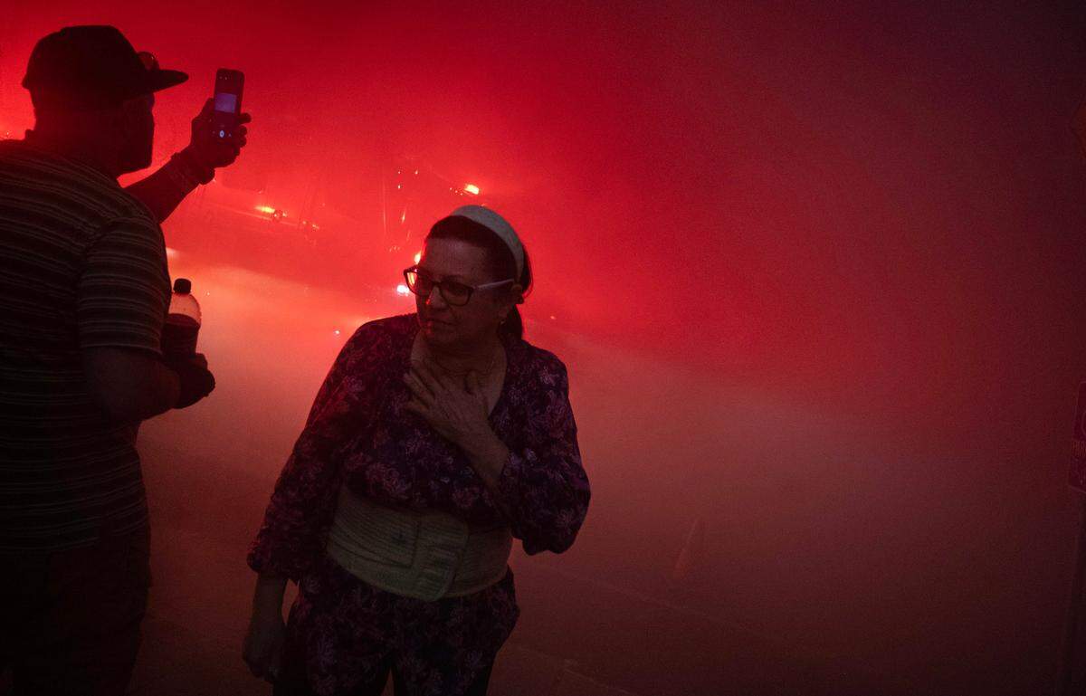 Neighbors brave heavy smoke as they watch the business fire on I Street in the Stadium District of Tacoma, Washington, on Thursday, Aug. 3, 2023.