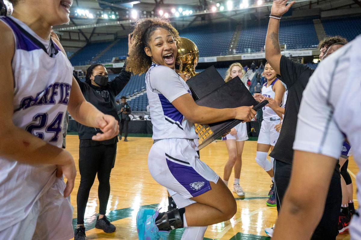 Garfield guard Malia Samuels (0) dances with the Class 3A basketball trophy after she helped lead her team past Lake Washington, 39-38, on Saturday, March 5, 2022, at the Tacoma Dome, in Tacoma, Wash.
