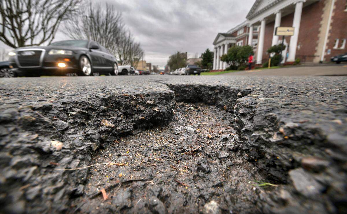 Traffic rolls past deep pothole on Tacoma Avenue South in Tacoma, Washington, on Wednesday, Jan. 5, 2022.