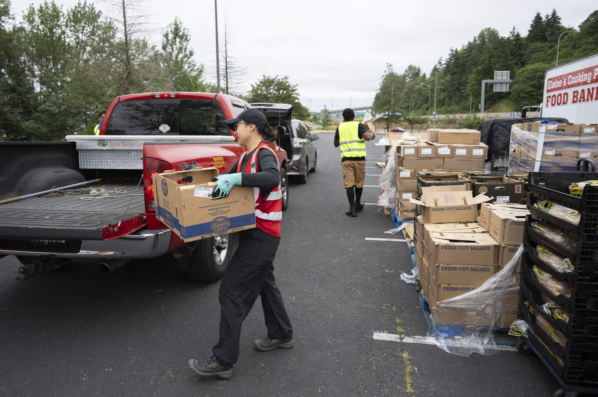 Carla Chavez, a warehouse associate with The Making A Difference Foundation, loads food into trunks during a drive through food distribution with Eloise’s Cooking Pot Food Bank on Wednesday, July 8, 2026, at the Tacoma Dome in Tacoma, Wash.
