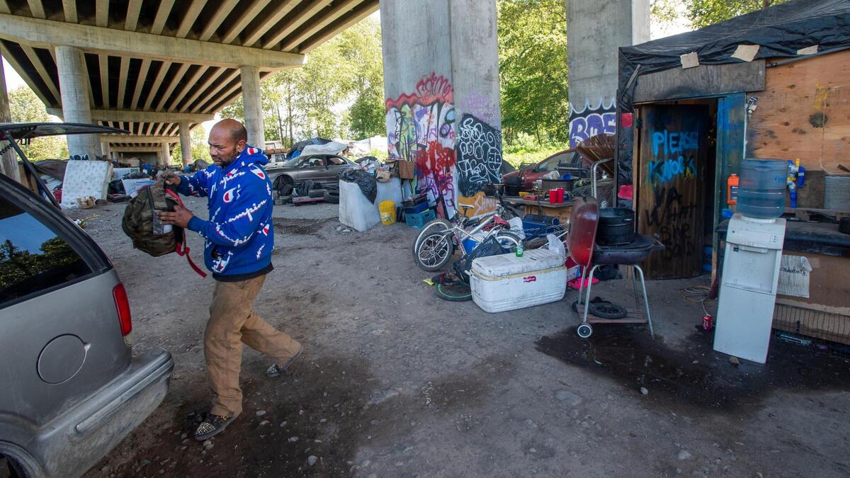 “Junior,” a 46-year-old man who describes himself as “address challenged,” transfers possessions from his makeshift home Saturday, June 5, 2021 in advance of the large encampment underneath the state Route 509 overpass being swept by the Port of Tacoma on June 10. Junior, who has lived at the site for three years, says structures in similar encampments on the east side of the Puyallup River have been knocked down previously. Junior says multiple strokes and a heart condition prevent him from working and this latest evacuation notice make his “feel disrespected, degraded, like I’m a lowlife.”
