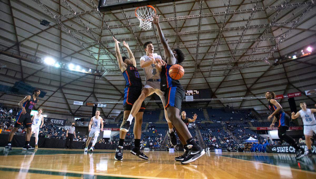 Gig Harbor’s Will Landram gets shut down at the basket by Rainier Beach defenders Myles Damon (left) and Josh Conerly Jr. during Thursday afternoon’s quarterfinal game of the WIAA 3A Boys Basketball State Championships tournament in the Tacoma Dome in Tacoma, Washington, on Thursday, March 3, 2022. Rainier Beach won the game, 65-60.