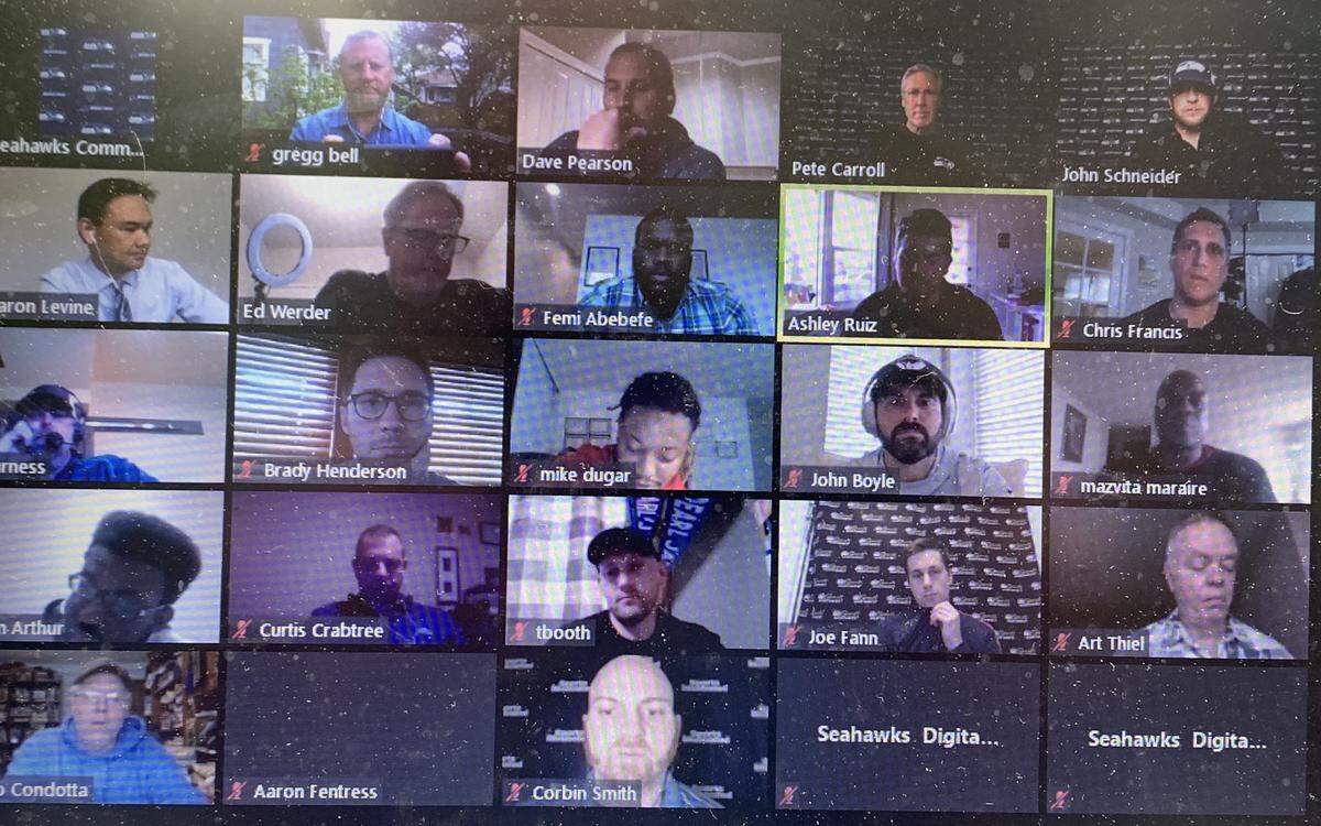 Seahawks coach Pete Carroll and general manager John Schneider (upper right) conduct a pre-draft news conference remotely from their Seattle-area homes via the Zoom online app Tuesday. Teams will extensively use Zoom to conduct this year’s virtual NFL draft like no other amid the coronavirus pandemic. The unpredictable begins Thursday evening.