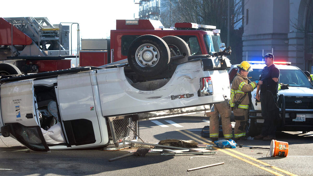 Paramedics tend to the driver of a City of Tacoma Public Works truck that was hit and rolled over, blocking Tacoma Avenue at 11th Street in downtown Tacoma, Washington, on Thursday, Jan. 27, 2022.