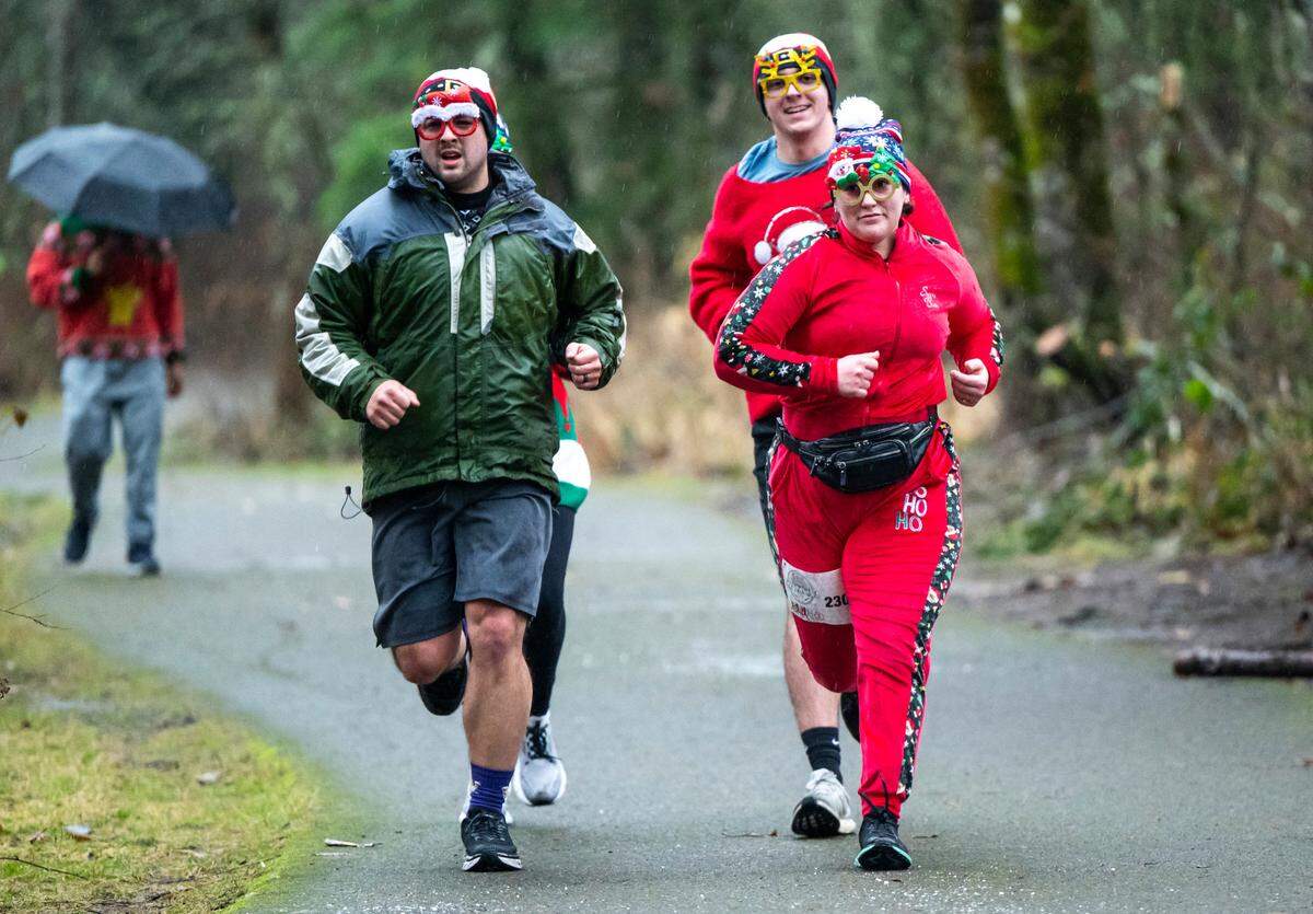A group of runners dressed in festive glasses and sweaters near the finish line during the 5th Annual Christmas Eve Ugly Sweater 5K on the Nathan Chapman Memorial Trail in Puyallup, Wash. on Dec. 24, 2022.